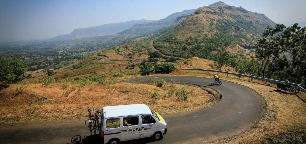 Cycling Competition in India - A car following a cyclist on a mountain slope road in deccan cliffhanger ultra race.