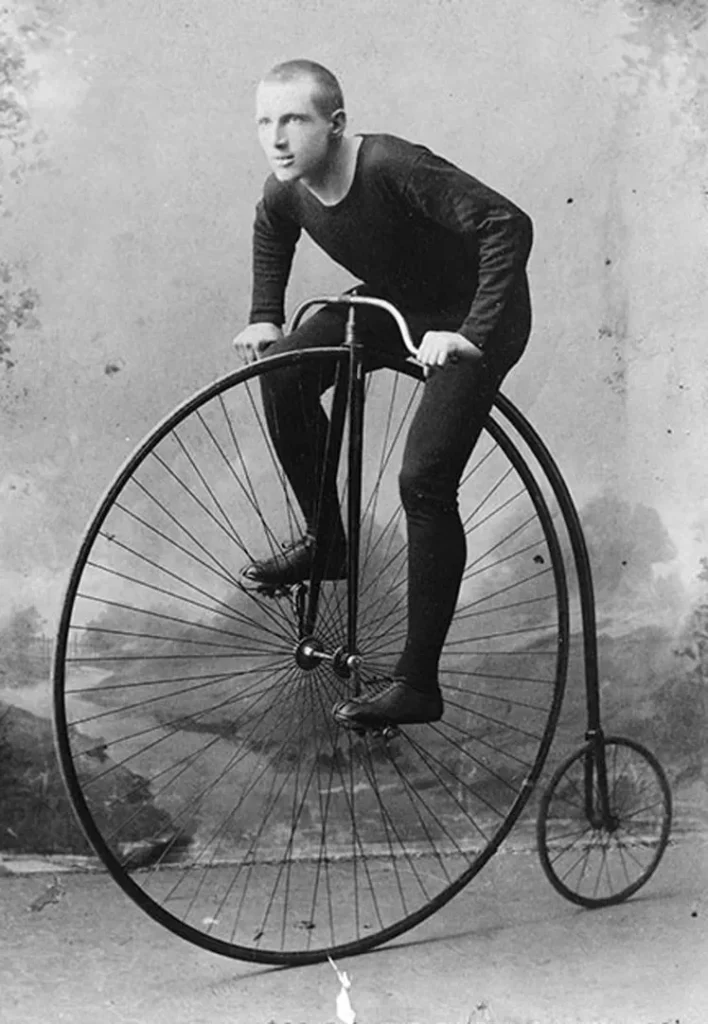 A person riding a high wheel bicycle in ancient times.