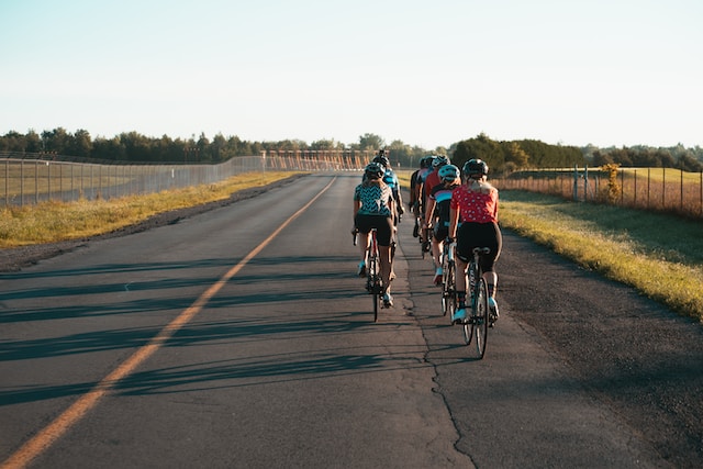 A group cyclist riding together in the evening on an empty road.