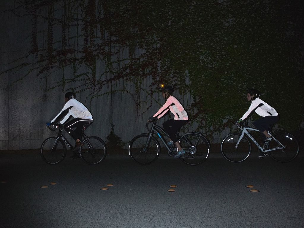 a group of people riding in night wearing a reflective vest