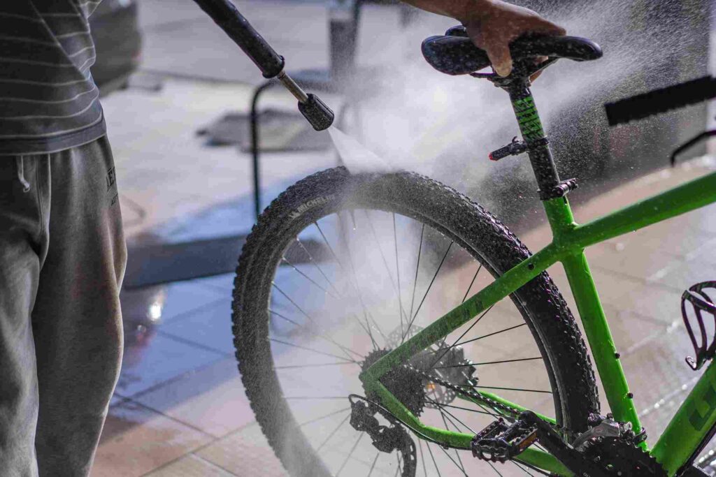 A person cleaning his green MTB using water spray.